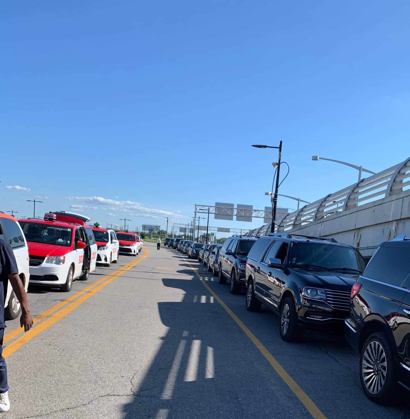 Luxe contre quotidien—Choix de transport pour le Grand Prix de Montréal 2025 Transports Grand Prix de Montréal 2025: Une flotte de limousines élégantes parfaitement alignées le long du mur, représentant le summum du luxe. Parallèlement à elles, une ligne de taxis avec un espace ample entre eux, offrant aux visiteurs les meilleures options de transport pour le Grand Prix de Montréal 2025.